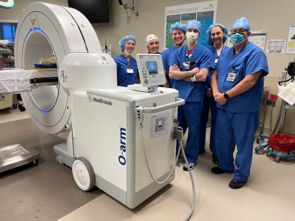 Doctors and nurses standing around the Medronic O-arm™ Surgical Imaging System