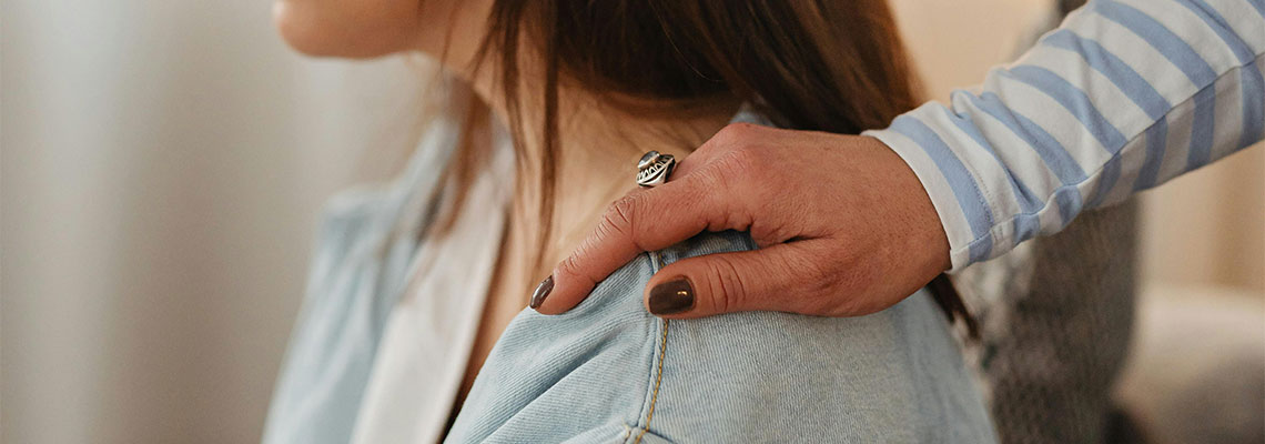 Tight focus of a hand on a woman's shoulder