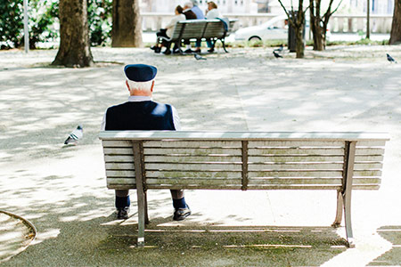 Small photo of an elderly man sitting on a park bench