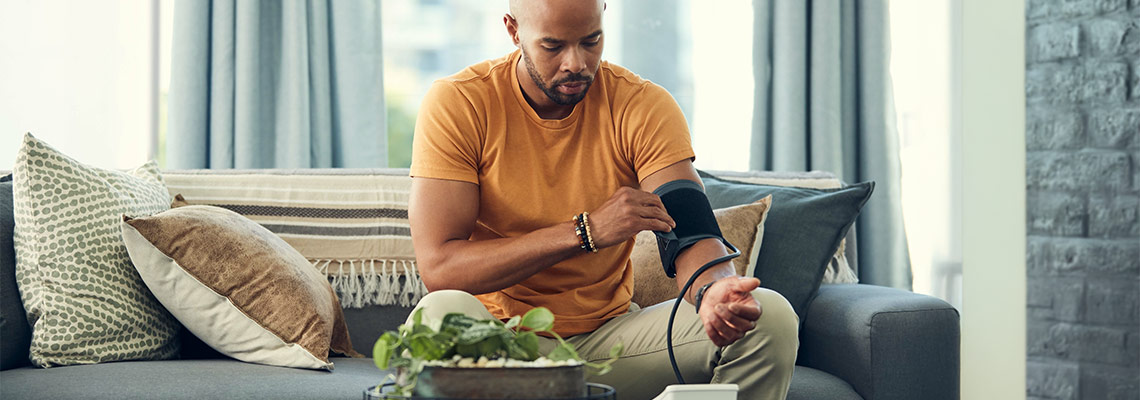 Man tightening an arm cuff as he takes his own blood pressure with a home blood pressure monitor